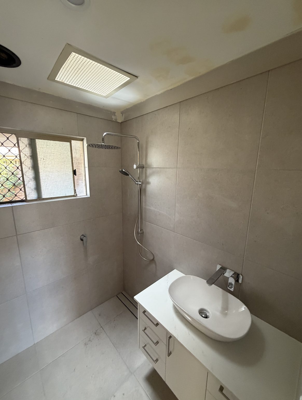 Bathroom after renovation in Perth — walk-in shower with rail shower, large-format tiles, strip drain and wall-hung vanity with vessel basin